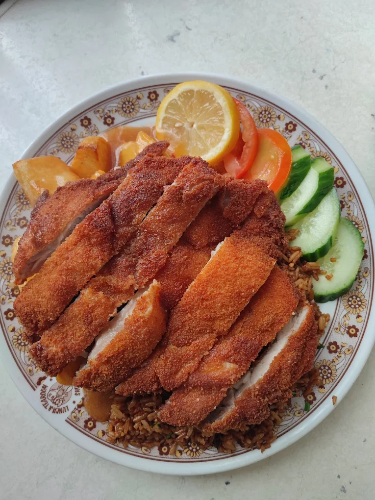 Krokante kipschnitzel met gebakken rijst, komkommer en citroen